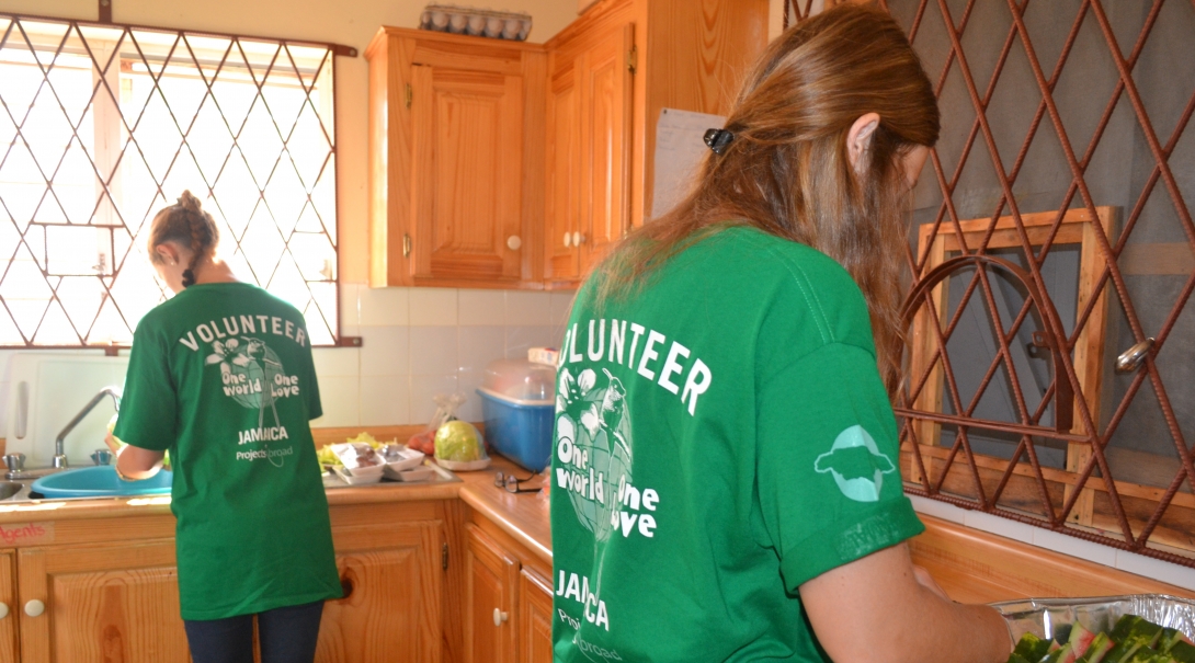 Two Projects Abroad volunteers prepare breakfast for students as part of their community work in Jamaica with a group. Volunteers working with children in Jamaica with a group help prepare a nutritious breakfast.